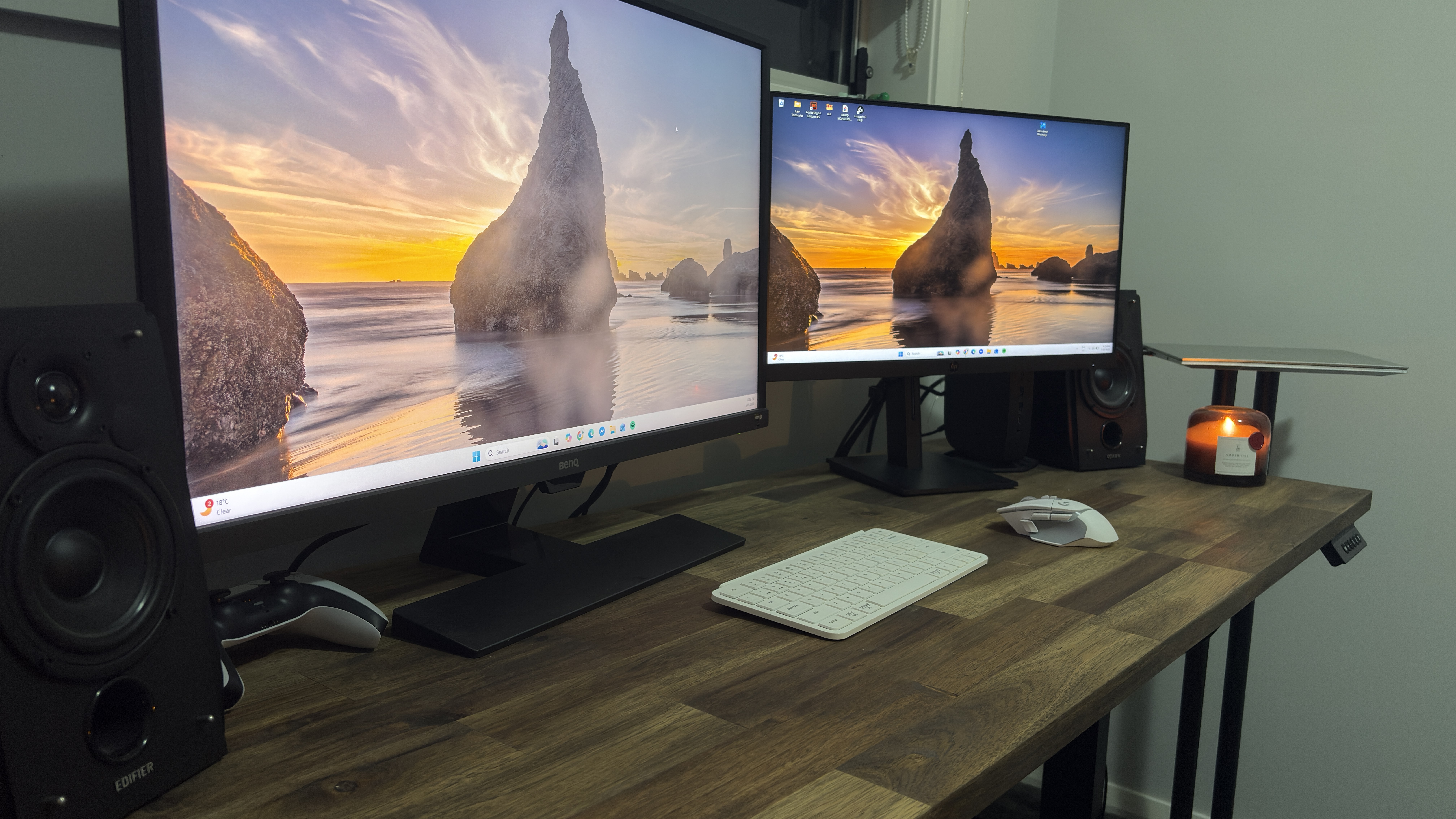 Wide custom standing desk with two monitors, speakers, keyboard, mouse, and candle